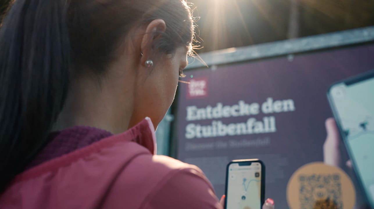 Frau scannt den QR-Code am Stuibenfall-Startschild und startet den wunderweg direkt im Browser